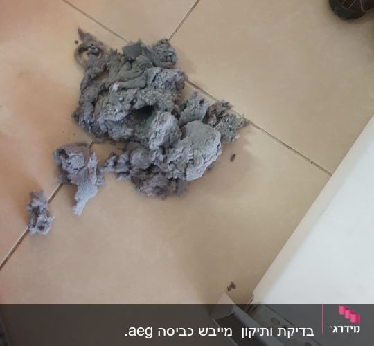 מכונת כביסה עם סיבי אבק על הרצפה